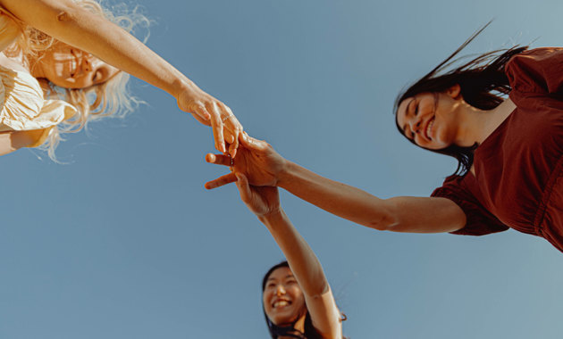 Tre damer holder hender